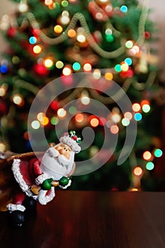 Santa Claus toy brings Christmas tree at blue snowy night bokeh