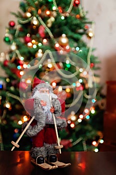 Santa Claus toy brings Christmas tree at blue snowy night bokeh