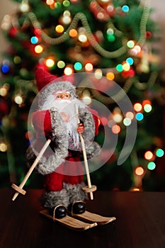 Santa Claus toy brings Christmas tree at blue snowy night bokeh