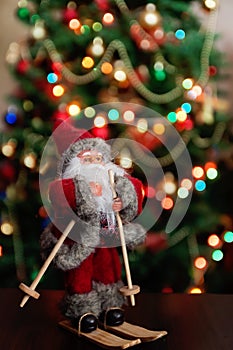 Santa Claus toy brings Christmas tree at blue snowy night bokeh