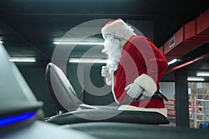 Santa Claus training at the gym on Christmas Day. Santa Claus running in machine treadmill at fitness gym club.