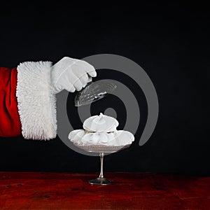 Santa Claus treats you to meringue, a sweet treat. Celebrate Christmas. Black background with copy space
