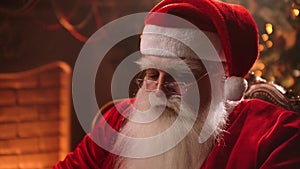 Santa Claus uses modern technology. Working at a laptop while sitting and typing on the keyboard. Online banking and