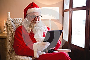 Santa claus using digital tablet in living room