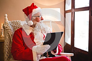 Santa claus using digital tablet in living room during christmas time