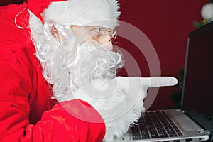 Santa Claus using laptop computer, pointing at screen