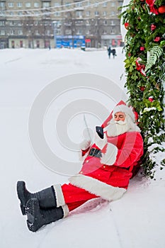 Santa claus using the phone outdoors. Merry Christmas.