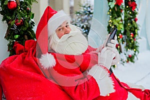 Santa claus using the phone outdoors. Merry Christmas.