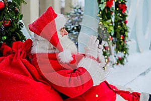 Santa claus using the phone outdoors. Merry Christmas.