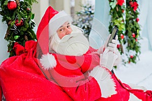 Santa claus using the phone outdoors. Merry Christmas.