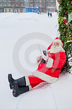 Santa claus using the phone outdoors. Merry Christmas.