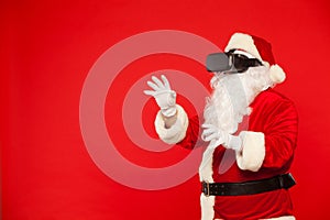 Santa Claus wearing virtual reality goggles, on a red background. Christmas