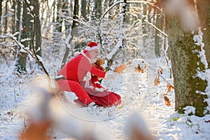 Santa Claus in winter forest with a bag of gifts read wish list on snow landscape.