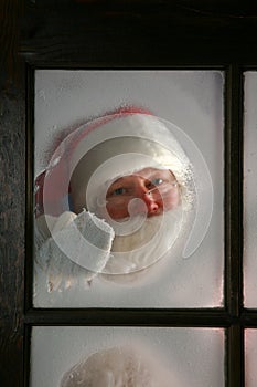 Santa Claus wipes the frost off his window to see outside on Christmas Eve