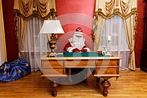 Santa Claus write a greeting card at the table