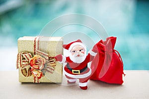 Santa Clause with gold gift box and red bag over blurred blue background