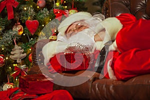 Santa Clause snoozing in a decorated living room with sack full