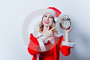 Santa Clous girl in red clothes with alarm clock