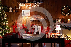 Santa costume hanging on chair at table with Merry Christmas decor in cozy home.