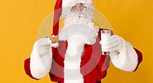 Santa eating cookie and drinking milk on orange background photo