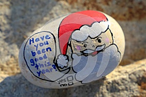 Santa face painted on a small rock Have you been good