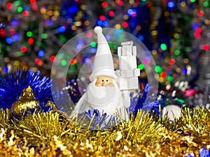 Santa figure with Christmas balls, tinsel on blurred lights background