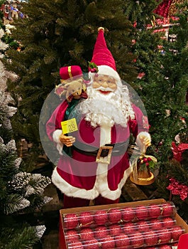 Santa among the fir trees. Toy on sale in the store, around the winter holidays. Preparations for Christmas.