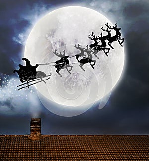 Santa flying over full moon and roof top