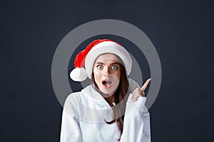 Santa Girl. Beautiful Woman In Christmas Hat Portrait. Excited Model Having Idea And Pointed Up.