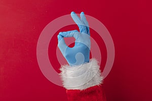 Santa hands wearing blue PPE protective gloves making OK hand gesture