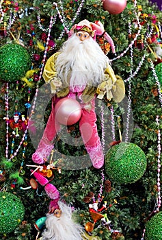 Santa hanging on a colourful decorated christmas tree