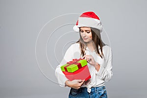 Santa hat Christmas woman holding christmas gift smiling happy and excited on grey background