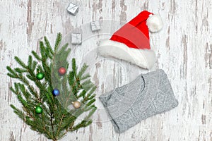 Santa hat, decorated with fir branch and a gray sweater on a woo