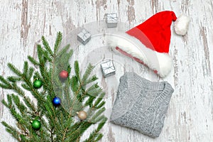 Santa hat, decorated with fir branch and a gray sweater on a woo