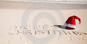 Santa Hat on white sandy beach and Merry Christmas