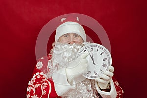 Santa is holding a white clock that says it& x27;s two minutes to twelve. close up