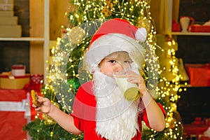 Santa in home. Santa Claus eating cookies and drinking milk on Christmas Eve. Kid Santa Claus enjoying in served