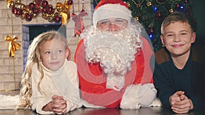 Santa and kids near the decorated Christmas tree. Wishes list
