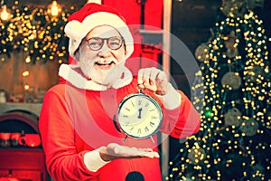 Santa make funny face and holding clock showing five minutes to midnight. Santa Claus holding alarm clock against