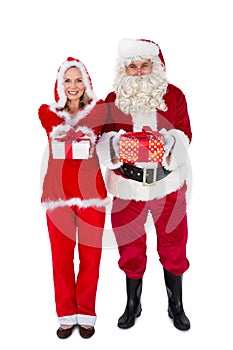 Santa and Mrs Claus smiling at camera offering gift