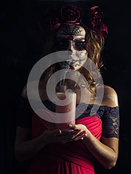 Santa muerte makeup young woman holding extinguished candle