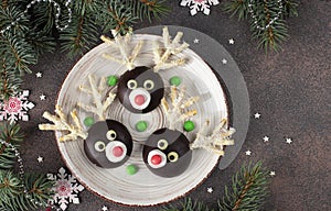 Santa reindeers made of cookies, chocolate, marshmallows and coconut flakes on plate on brown background. Christmas