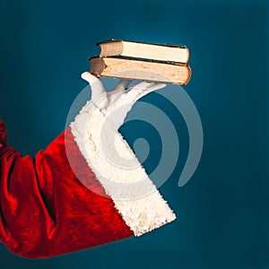 Santa's hand with an two old book on a blue background with copy space