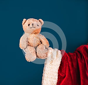 Santa\'s hand in a white glove holds a teddy bear. A Christmas gift. Concept for child protection. Space for text