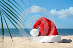 Santa`s hat on sandy beach, space for text. Christmas vacation