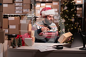 Santa scanning barcode on delivery parcel. Worker scan barcode of cardboard packages before delivery at storage working