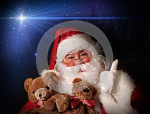 Santa smiling holding toy teddy bears