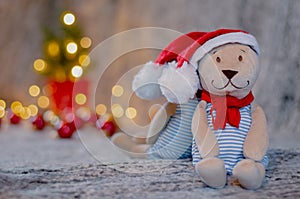 Santa teddy bear doll wearing santa hat with bokeh light background of Christmas tree
