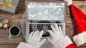 Santa using laptop with Christmas snowflakes