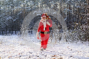 Santa in the winter field. Santa Claus on Christmas Eve is carrying presents to children in a bag full length.